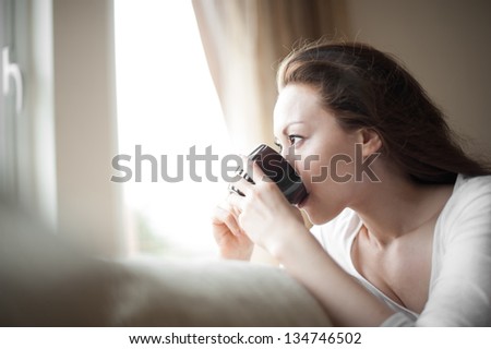 Attractive mixed female lifestyle drinking a cup of coffee looking out