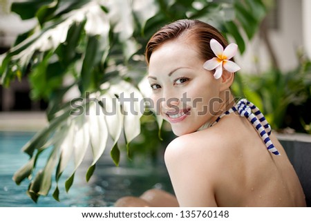 Attractive Asian Female smiling near a pool with flower in the hair