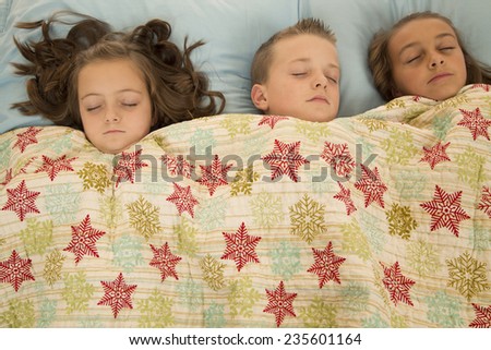 three children asleep under a snowflake blanket