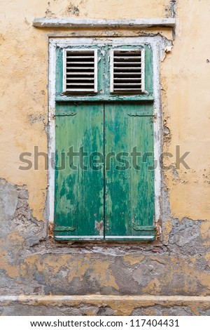 Weathered green window shutters. Weathered green window shutters and old wall with pealing paint and cracking plaster. Photographed in Willemstad, Curacao, Netherlands Antilles.