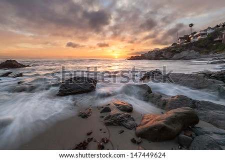 Rocky coastal beach sunset seascape with dramatic sky. This is an image of a rocky coastal beach scene taken at sunset with a dramatic sky.  Photo was taken at Moss Cove, Laguna Beach, California.