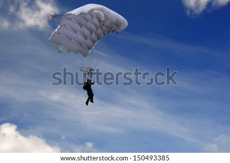 Skydiver moving down in high speed just before landing. Background with blue sky with clouds.