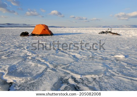 Bicycle tourists?? winter camp Ã?Â¢?? orange tent and bikes on the surface of frozen lake in morning light