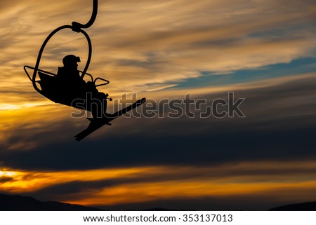 Silhouette of lonesome skier climbing up by the chair lift in sunrise