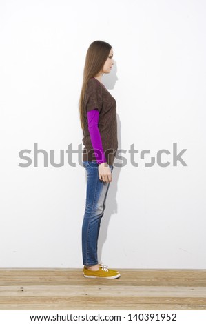 Full length attractive young girl in jeans standing on wooden floor