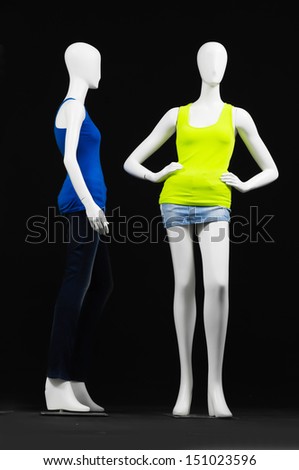 Two mannequin dressed in green and blue shirt and trousers on black background