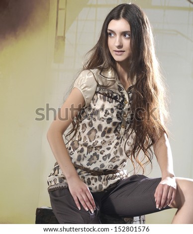 Young girl with long hair is in fashion style sitting on cube