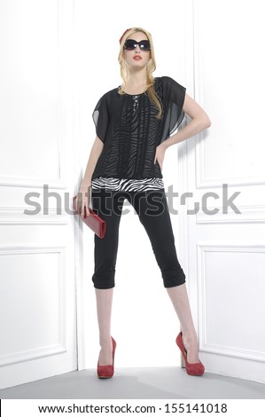 Full body fashion model in sunglasses holding purse posing in studio