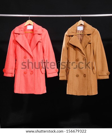 Two female coat on hangers at the show-black background