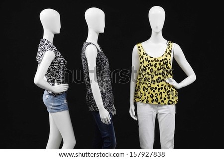 Three mannequin dressed in shirt and trousers on black background
