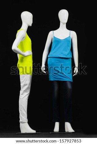 full-length two mannequin dressed in blue and green shirt and trousers on black background