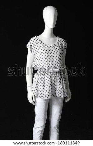 mannequin dressed in shirt and white trousers on black background