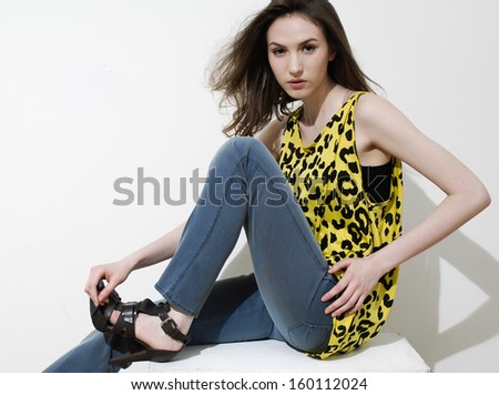 The fashionable young woman in jeans sitting cube