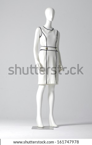 Mannequin dressed in white evening gown on gray background