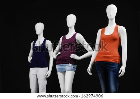 Three mannequin female dressed in colorful shirt and trousers on black background