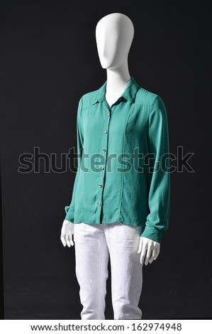 Mannequin female dressed in blue shirt with white trousers on black background