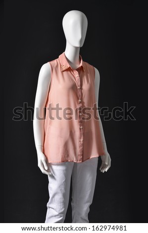 Mannequin female dressed in shirt and white trousers on black background