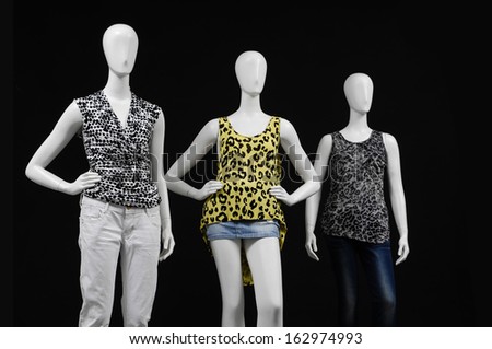 Three mannequin female dressed in fashion shirt and trousers on black background