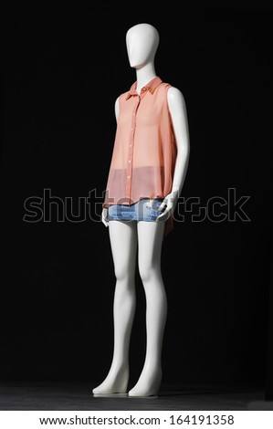 full-length mannequin in shirt and jeans shorts-black background