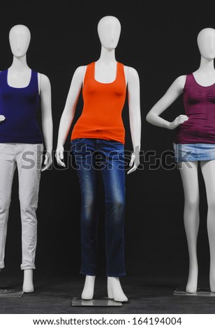 Three mannequin dressed in colorful shirt and jeans on black background