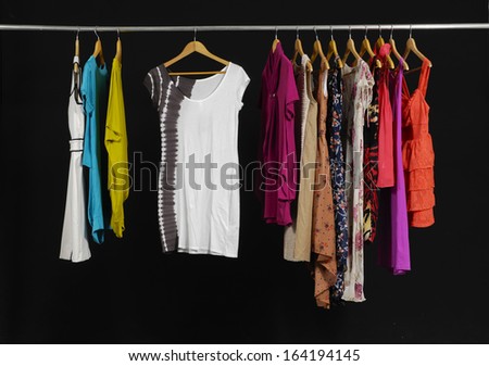 Variety of casual fashion clothing hanging on hangers on black