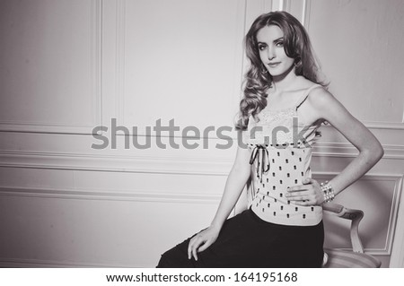 Portrait of an attractive young woman sitting in old chair studio shoot- black and white