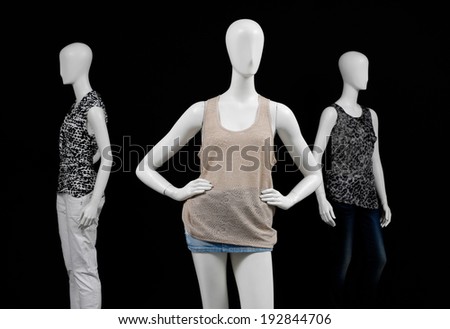 Three mannequin female dressed in shirt and short jeans and trousers on black background
