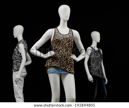 Three mannequin female dressed in shirt and short jeans and trousers on black background
