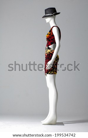 Mannequin dressed in fashion dress with hat on gray background