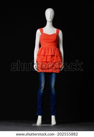 full-length mannequin in female dressed in orange shirt and jeans on black background