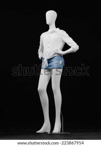 Full length female mannequin in shirt dress and shorts on black background