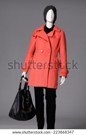 female clothing in hat with orange coat and bag on mannequin