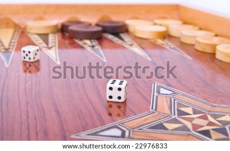Wooden handmade backgammon board with chips and two dices on white background