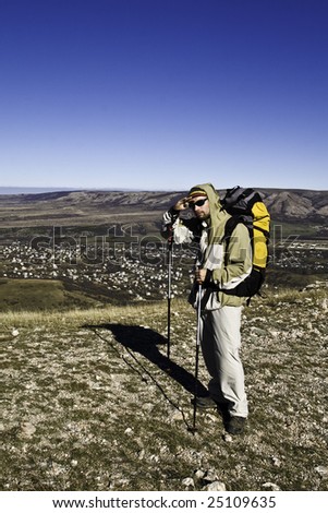 Hiker in sunglasses and with hiking poles on mountain summit looking ahead