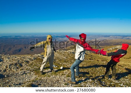 Happy hikers wave their hands and playing with strong wind on mountain summit
