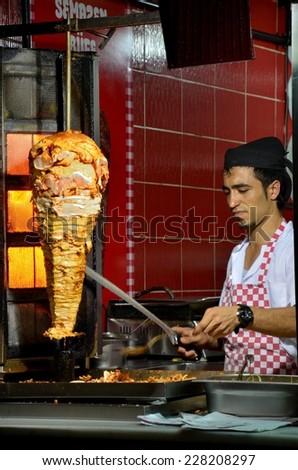Istanbul, Turkey - October 26, 2012: A doner kebab vendor and grill. A doner kebab chef cuts meat from his rotisserie at a roadside cafe in Istanbul\'s Sultan Ahmet district.