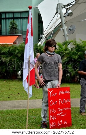 Singapore - May 1, 2013: A young man with a Singapore flag & placard during a May Day rally held in Singapore Speakers\' Corner, Hong Lim Park held to protest the government\'s immigration policies.