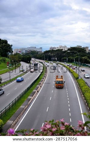 Singapore - January 2, 2013: Cars, light heavy trucks & other vehicles flow on a road in the Braddell district, Singapore. Road dividers with foliage & flowers are visible.