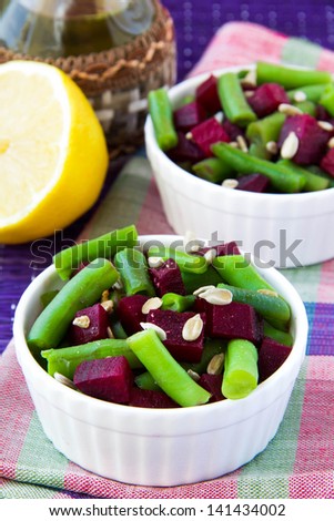 Fresh bright salad with green bean-pods and roasted beetroot with sunflower seeds in white bowl