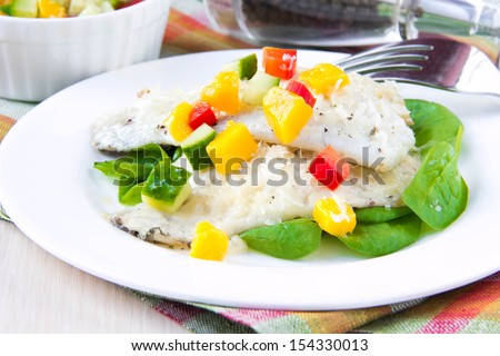 Fried filet of white fish Dorado on bed of fresh spinach and salsa with mango, cucumber and red pepper