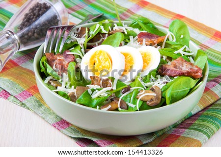Delicious, generous and fresh salad with spinach, bacon, champignon mushrooms, cheese and boiled eggs with bright yolk