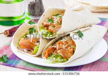 Wrapped in a tortilla roll with spicy fried chicken and vegetables salad, tasty Mexican dish