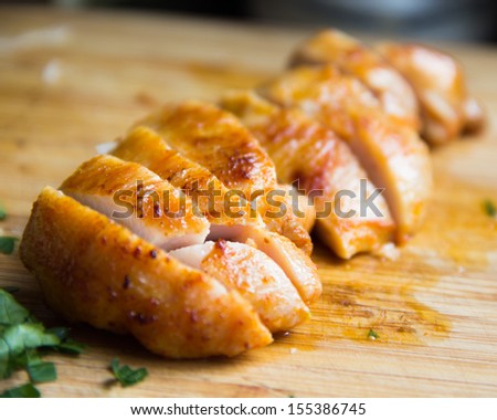 Sliced grilled juicy chicken fillet on wooden board macro, clouse up