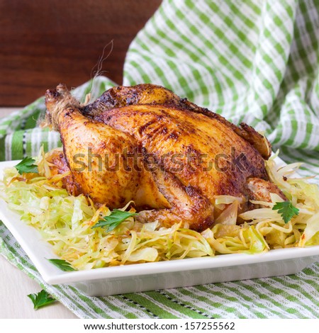 Roasted whole chicken with golden crust and garnish of stewed cabbage, tasty dinner