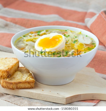 Chicken soup with noodles, carrots, eggs and cheese croutons, tasty dinner