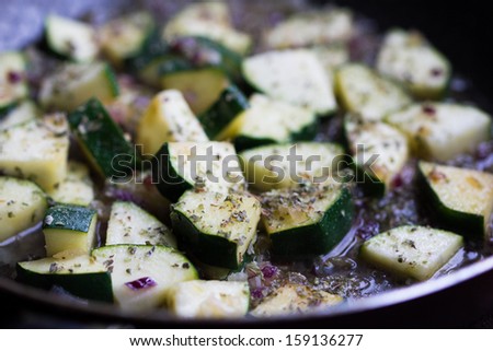 Cut into triangles zucchini fried in sauce with onions and herbs, cooking homemade dinner