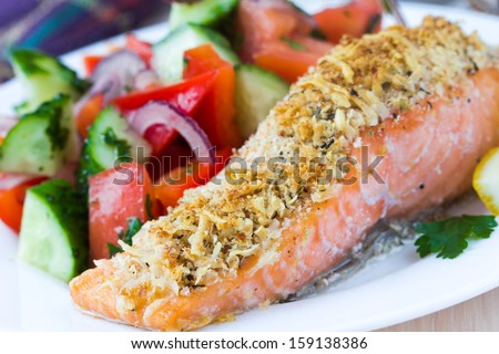 Steak fillet of red fish salmon with cheese crust breading and fresh vegetable salad