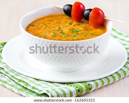 Vegetable soup in white bowl with olives and tomato, tasty diet dinner