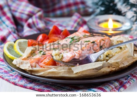 Salmon steak with rice, herbs, tomatoes, baked in parchment paper, tasty dinner