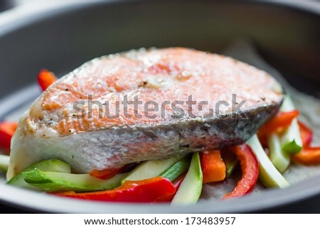Cooking steak of red fish salmon on vegetables, zucchini, sweet pepper, delicious homemade dish